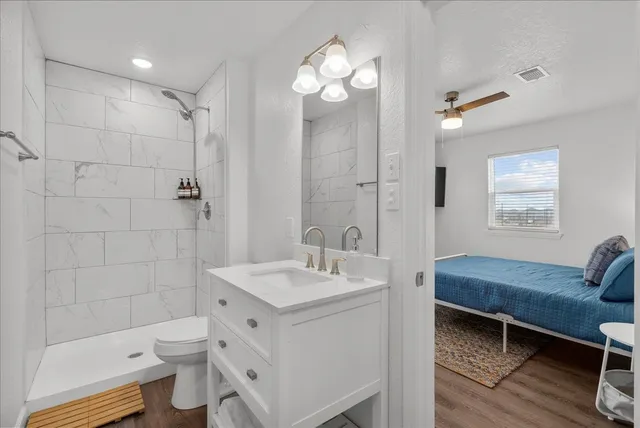 a bathroom with a sink a toilet a mirror and shower