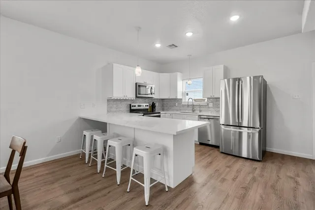 a kitchen with stainless steel appliances granite countertop a white cabinets and wooden floor