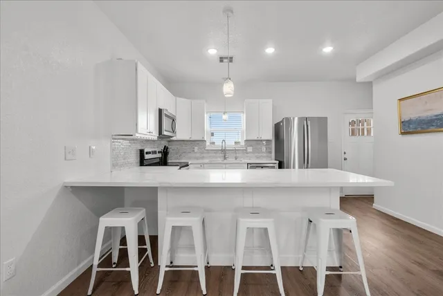 a kitchen with stainless steel appliances granite countertop a dining table chairs refrigerator and microwave