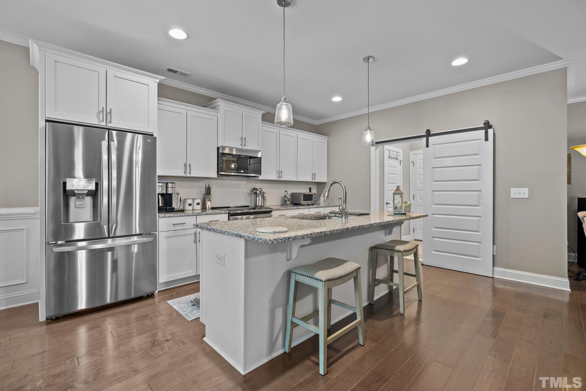 391 River Ridge Lane Timberlake, NC 27583 - Photo 12 of 47 a kitchen with kitchen island a refrigerator a stove a sink and white cabinets with wooden floor
