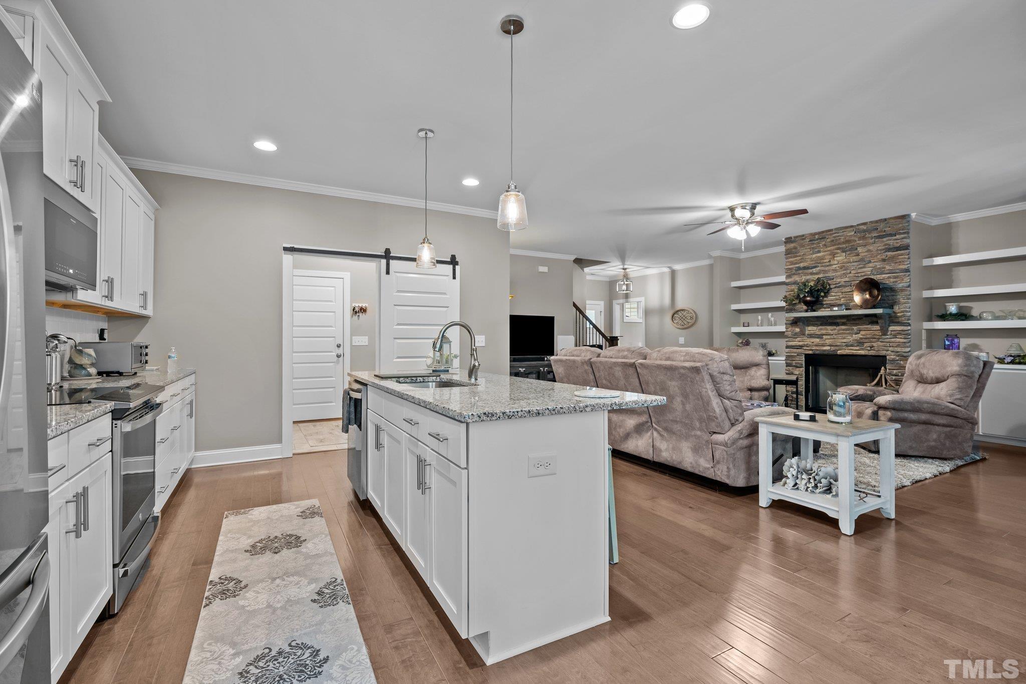 391 River Ridge Lane Timberlake, NC 27583 - Photo 13 of 47 a kitchen with stainless steel appliances kitchen island granite countertop a stove top oven a sink a dining table and chairs with wooden floor
