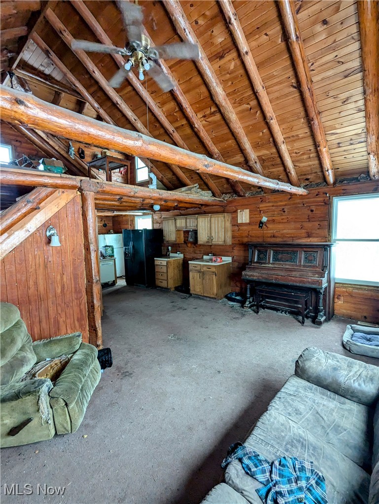 36808 Kinney Ridge Road Woodsfield, OH 43793 - Photo 9 of 9 Unfurnished living room with ceiling fan, vaulted ceiling with beams, wood walls, and wooden ceiling