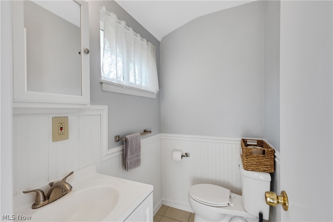 6895 Revere Road Cleveland, OH 44130 - Photo 27 of 33 Half Bath featuring vanity, toilet, lofted ceiling, and tile patterned flooring