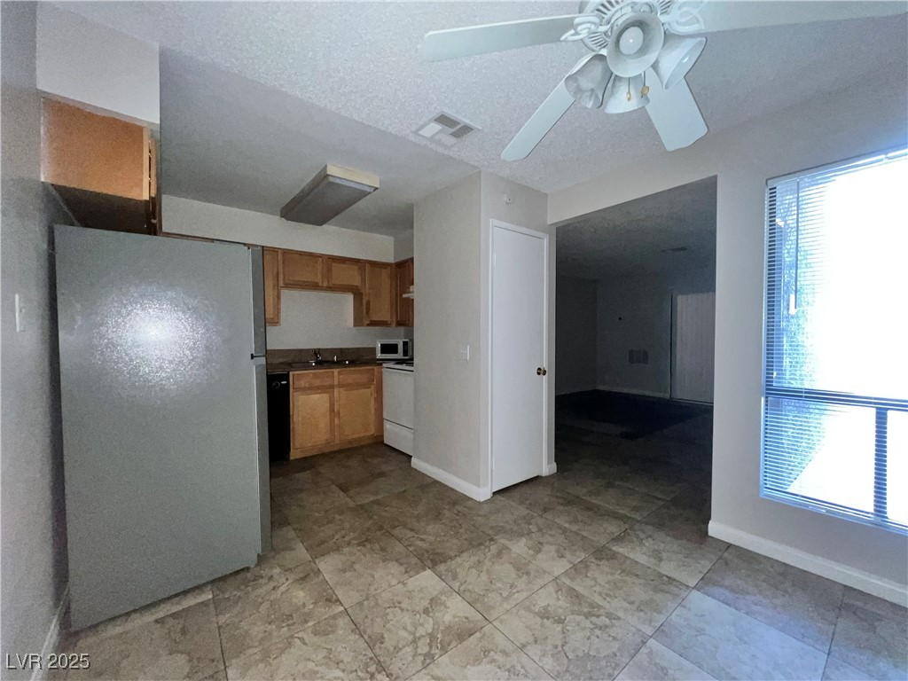 3151 North Soaring Gulls Drive, Unit 1150 Las Vegas, NV 89128 - Photo 7 of 17 Kitchen with freestanding refrigerator, a ceiling fan, white range oven, and a textured ceiling