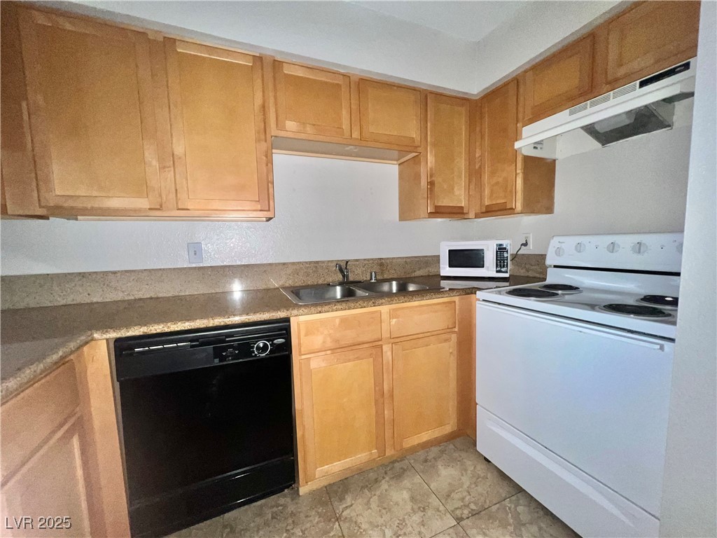 3151 North Soaring Gulls Drive, Unit 1150 Las Vegas, NV 89128 - Photo 10 of 17 Kitchen with white appliances, under cabinet range hood, and light tile patterned floors