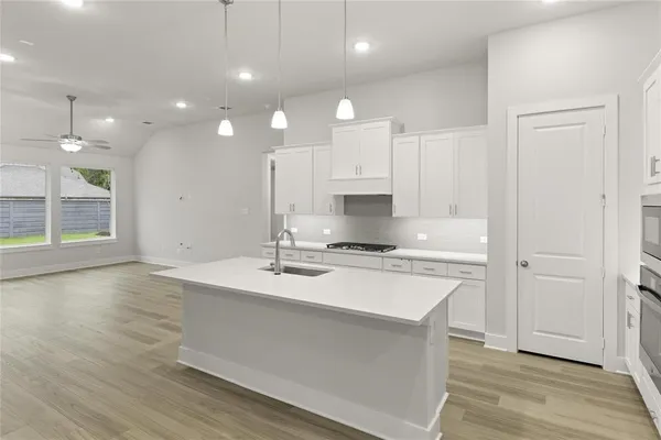 a large kitchen with stainless steel appliances a large counter top a stove and a wooden floors