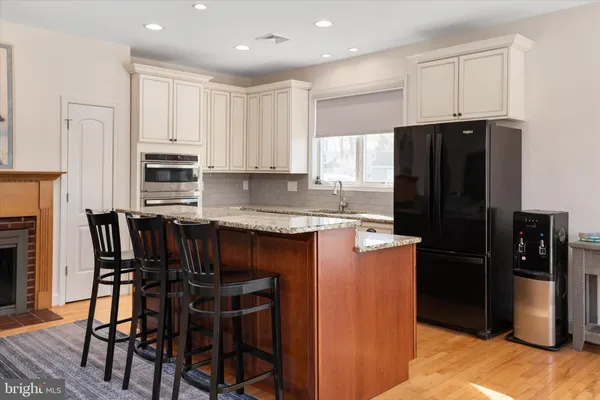 a kitchen with stainless steel appliances granite countertop a stove a sink and a refrigerator with wooden floors