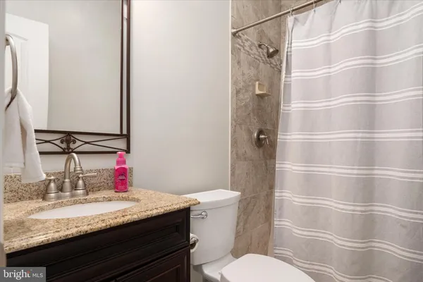 a bathroom with a granite countertop sink a toilet and shower