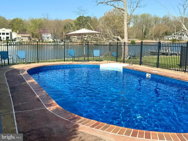 a view of swimming pool with a table and chairs under an umbrella
