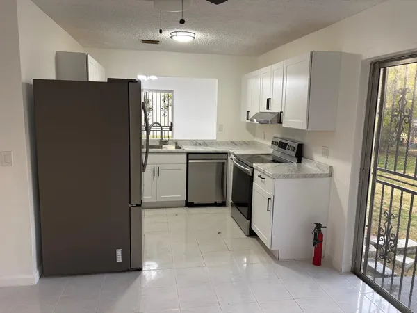 a kitchen with stainless steel appliances granite countertop a refrigerator a sink a stove and white cabinets