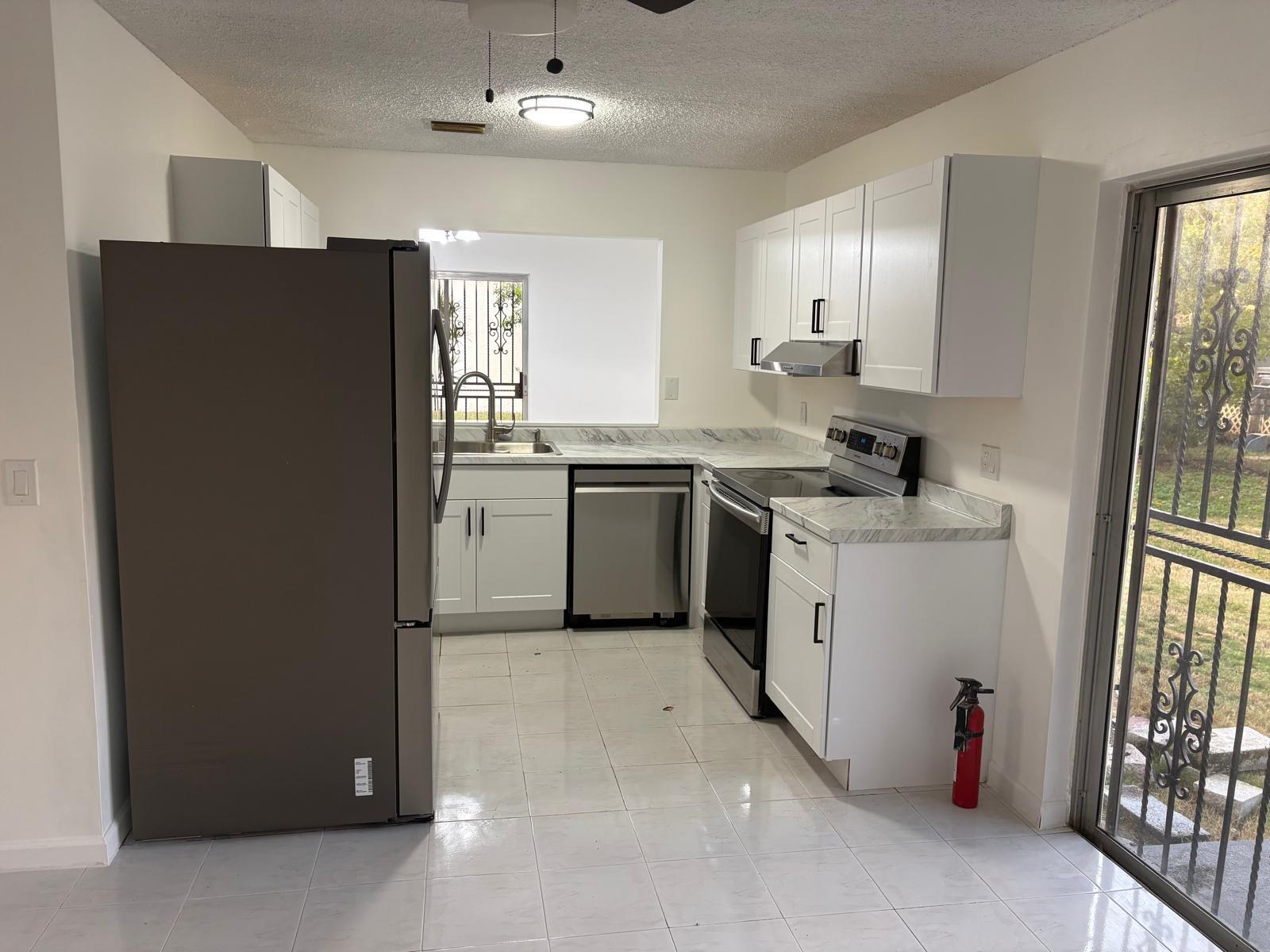 12231 Southwest 210th Street Miami, FL 33177 - Photo 19 of 38 a kitchen with stainless steel appliances granite countertop a refrigerator a sink a stove and white cabinets