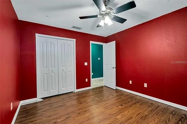 an empty room with wooden floor closet and windows