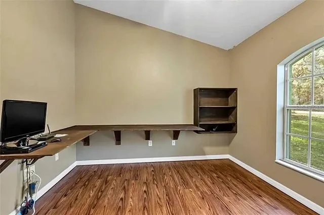 a living room with a flat screen tv on dresser and a wooden floor
