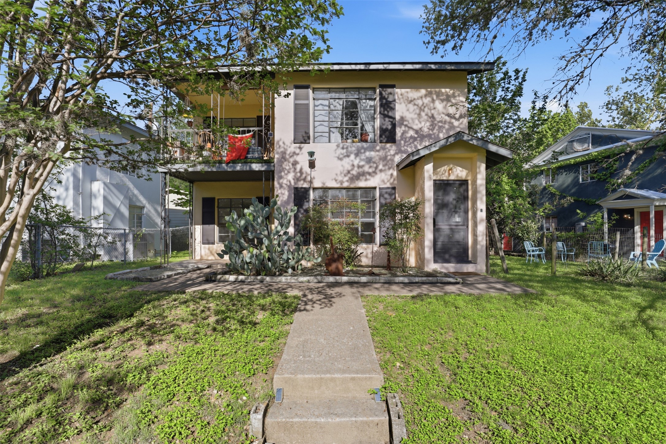 Cream-colored stucco exterior featuring multiple windows and a covered entrance.