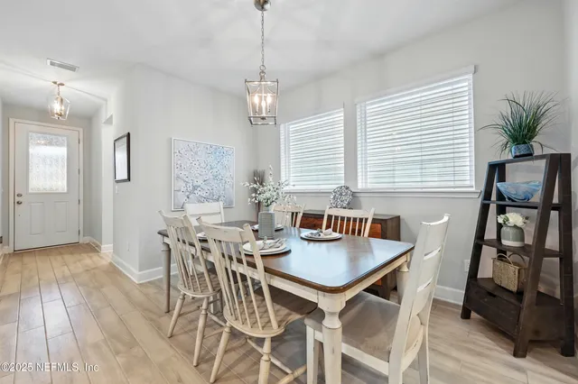 a view of a dining room and livingroom view with furniture wooden floor a rug a flat screen tv a painting and a chandelier