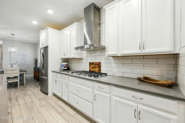 a kitchen with stainless steel appliances granite countertop a dining table chairs microwave and sink