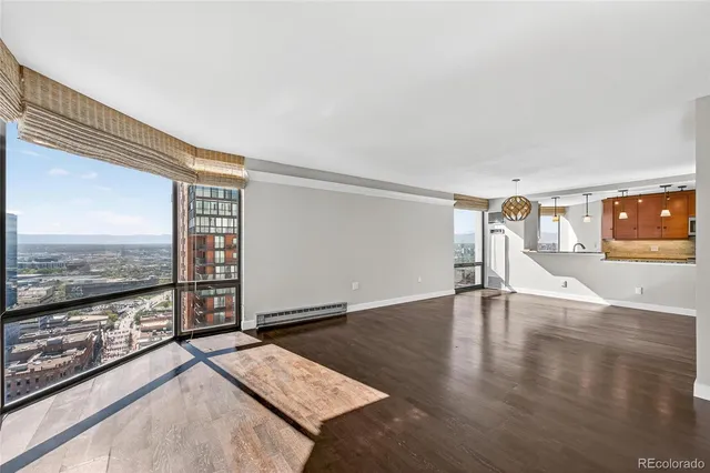 a view of an empty room with wooden floor and a fireplace