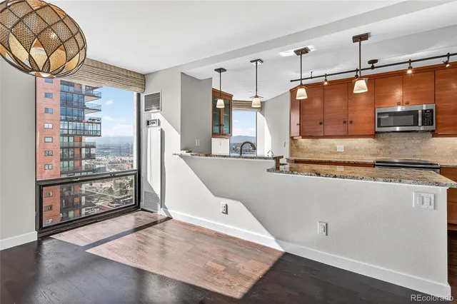 a kitchen with stainless steel appliances wooden floor and a refrigerator