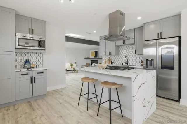 a kitchen with stainless steel appliances kitchen island granite countertop a refrigerator a sink dishwasher a stove and white cabinets with wooden floor