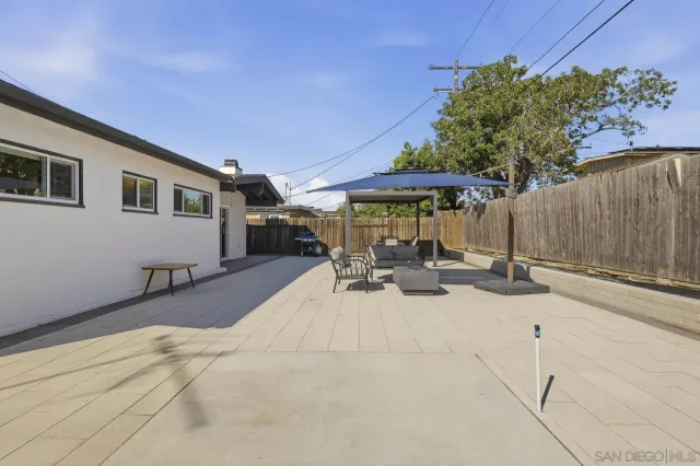 a view of a patio with table and chairs under an umbrella with wooden fence
