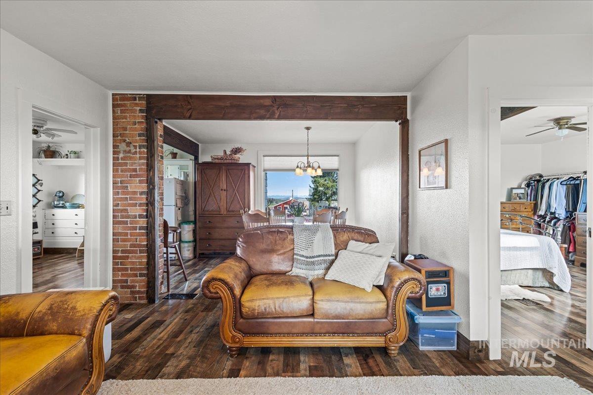 19454 Idaho Road Worley, ID 83876 - Photo 20 of 39 Open concept living area featuring wood-finish flooring, exposed brick accents, and a substantial timber beam