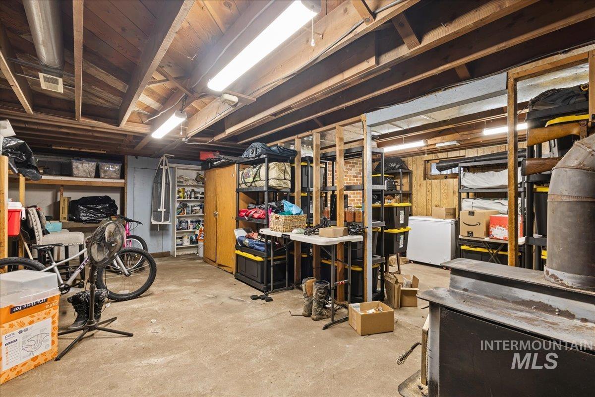 19454 Idaho Road Worley, ID 83876 - Photo 25 of 39 Utility space featuring exposed ceiling joists, concrete flooring, wood paneling, and fluorescent lighting fixtures
