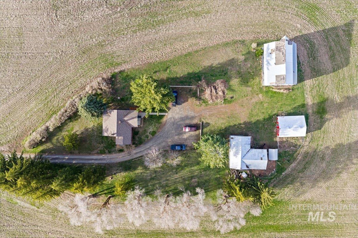 19454 Idaho Road Worley, ID 83876 - Photo 37 of 39 Aerial depiction of a property featuring multiple structures, including a primary residence with a brown shingle roof, several outbuildings with white roofs, and a long, curving driveway