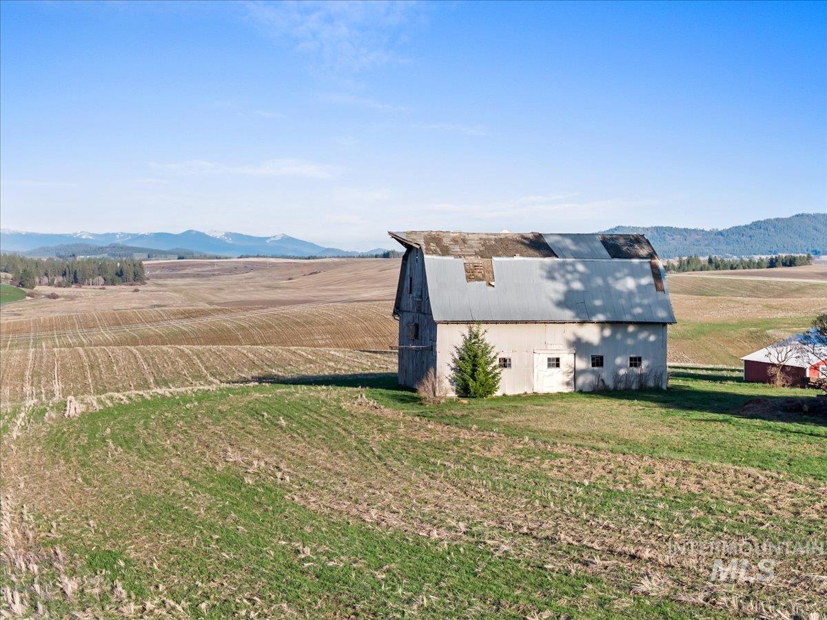 19454 Idaho Road Worley, ID 83876 - Photo 5 of 39 Expansive agricultural land featuring a large barn with a metal roof and an additional red outbuilding