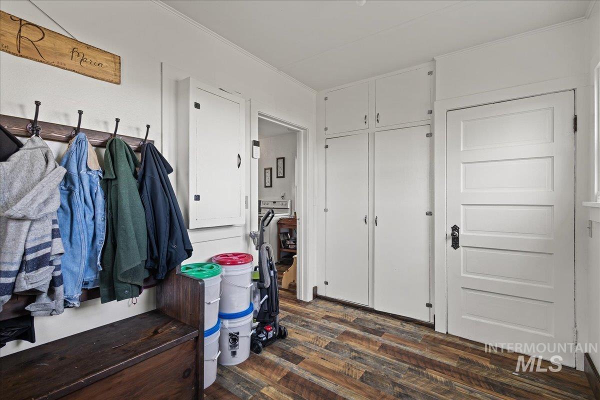 19454 Idaho Road Worley, ID 83876 - Photo 8 of 39 Entryway featuring wood-finish flooring, built-in storage cabinets, a five-panel interior door with dark hardware, and white trim molding