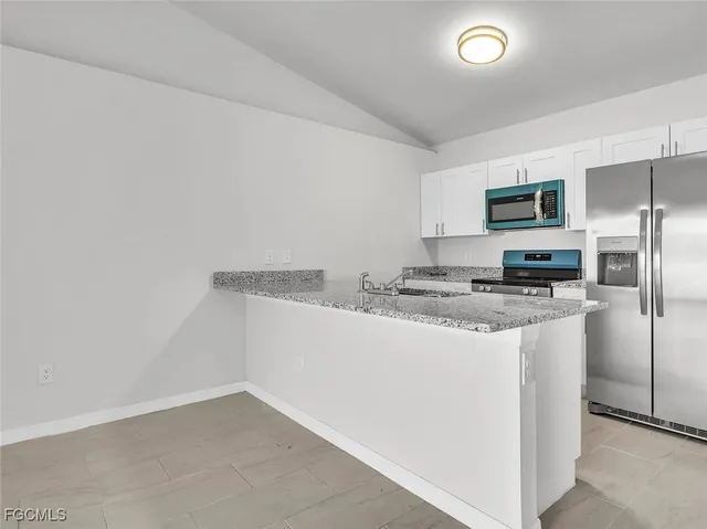 a kitchen with granite countertop a refrigerator and a stove top oven