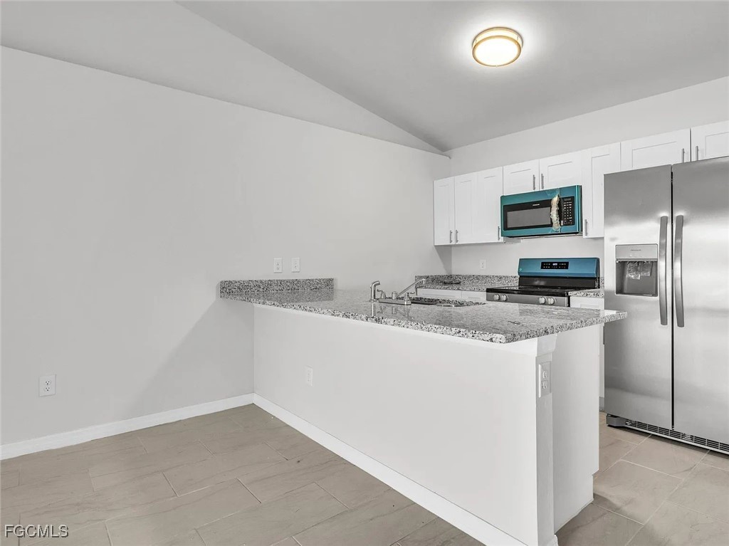 4622 Southwest 8th Court Cape Coral, FL 33914 - Photo 2 of 8 a kitchen with granite countertop a refrigerator and a stove top oven