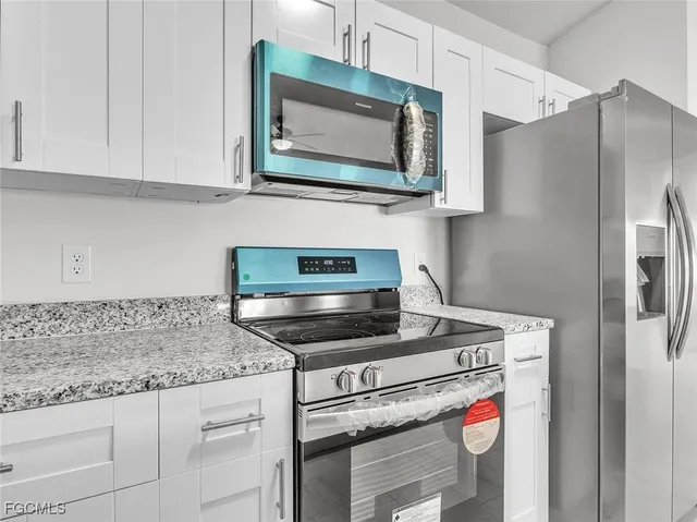 a kitchen with stainless steel appliances granite countertop a stove microwave and refrigerator