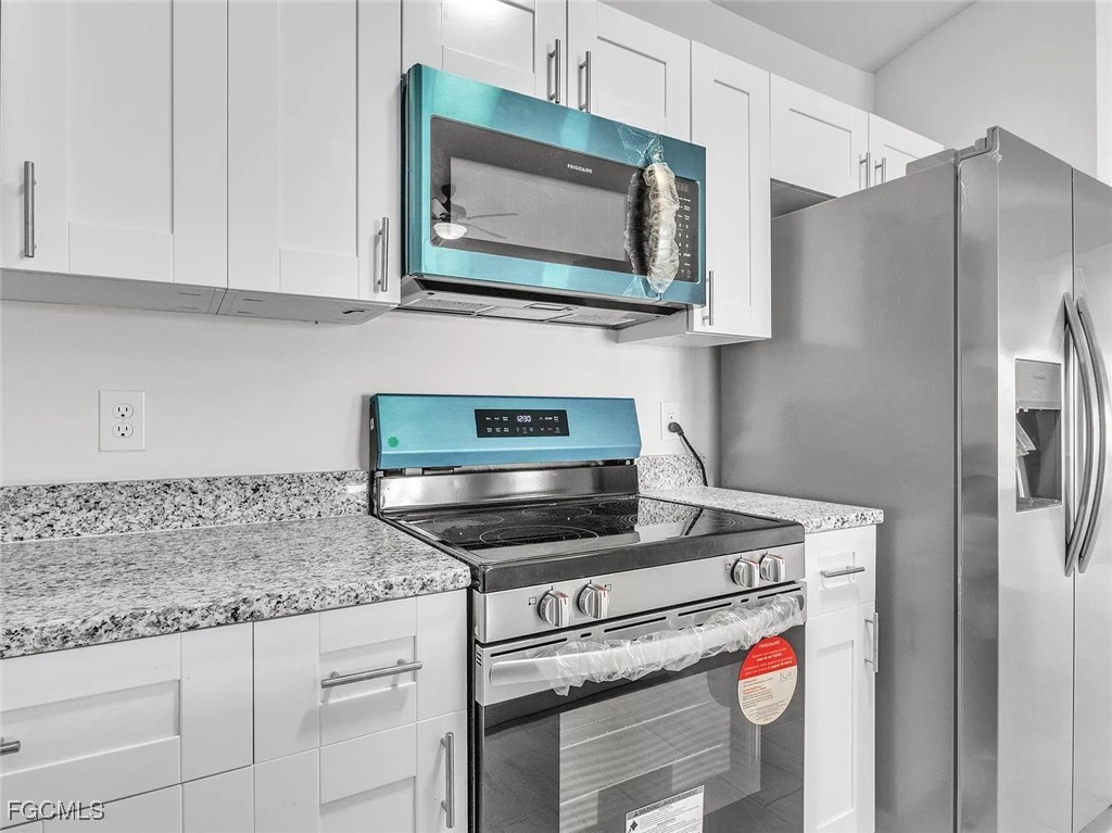 4622 Southwest 8th Court Cape Coral, FL 33914 - Photo 3 of 8 a kitchen with stainless steel appliances granite countertop a stove microwave and refrigerator