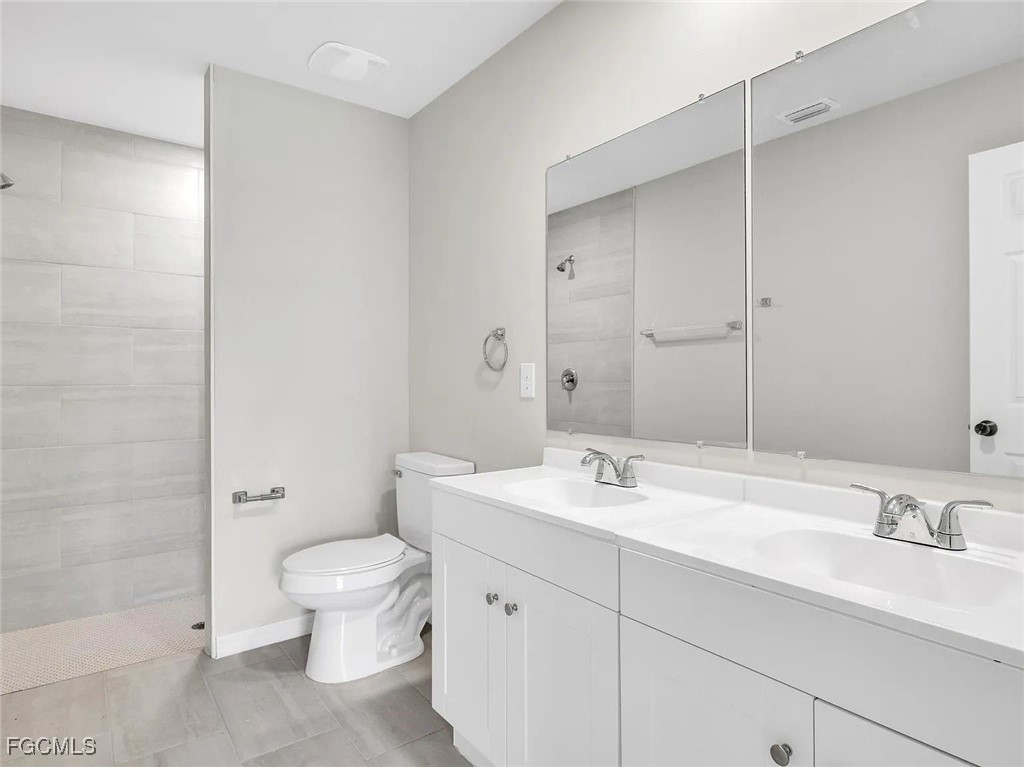 4622 Southwest 8th Court Cape Coral, FL 33914 - Photo 5 of 8 a bathroom with a double vanity sink toilet and a mirror