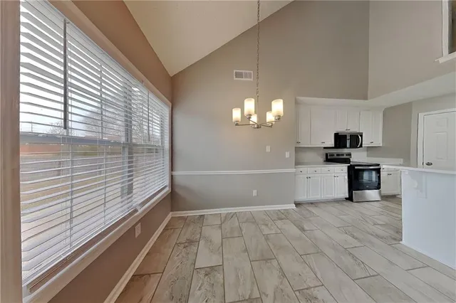 a view of empty room with wooden floor and chandelier