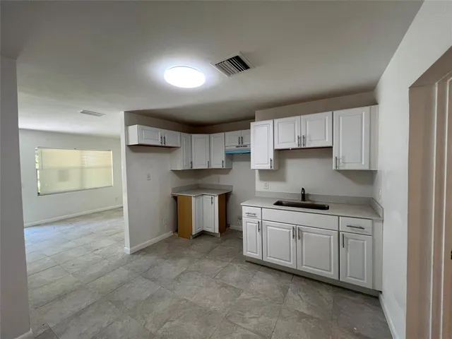 a kitchen with granite countertop a stove top oven a sink a counter space and cabinets