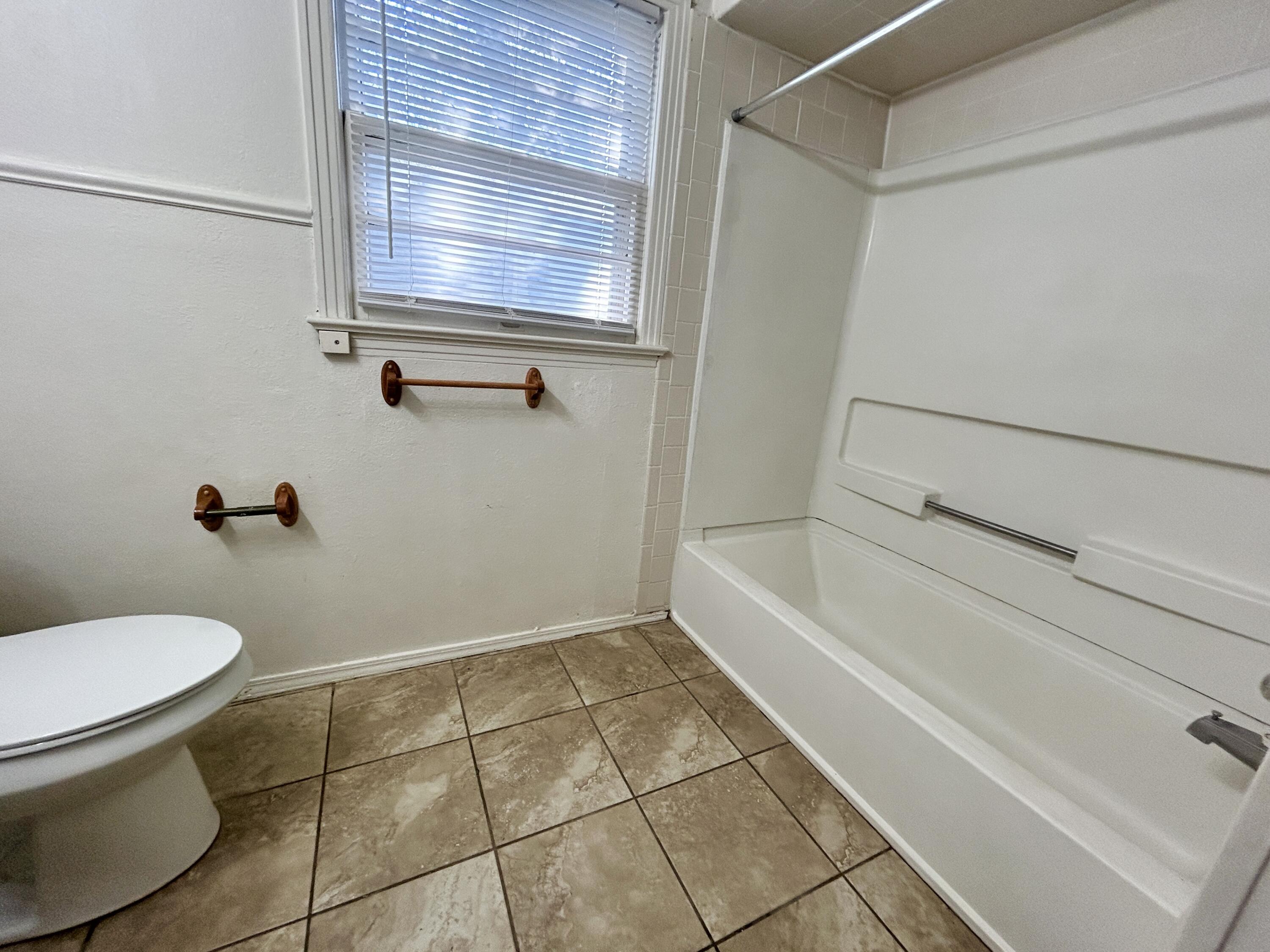 2216 30th Street, Unit FRONT Lubbock, TX 79411 - Photo 6 of 11 a bathroom with a toilet and a bath tub