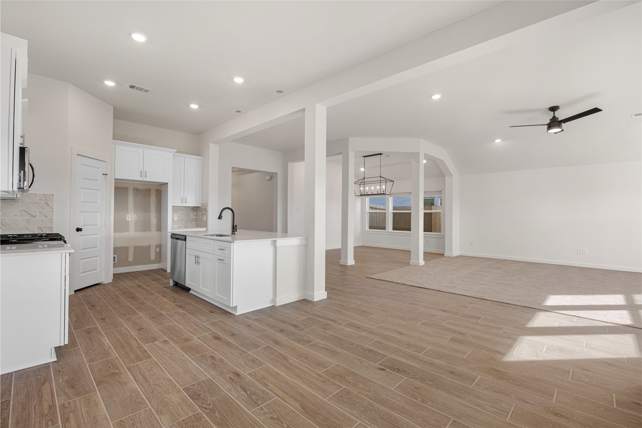 3222 Emerald Hills Drive Angleton, TX 77515 - Photo 15 of 31 a large white kitchen with kitchen island a stove a sink a refrigerator and white cabinets with wooden floor