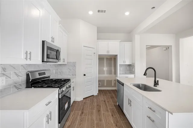 a kitchen with kitchen island stainless steel appliances a sink stove and refrigerator