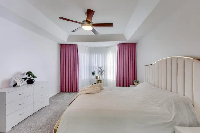 a bedroom with a large bed and a chandelier fan