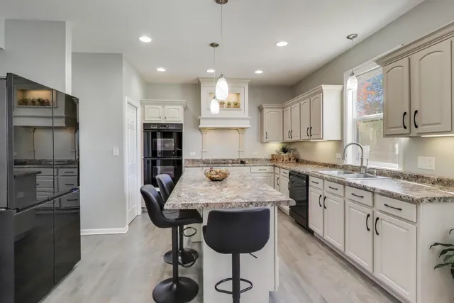 a large kitchen with granite countertop a center island stainless steel appliances and cabinets