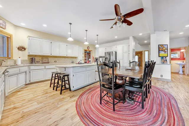 a kitchen with stainless steel appliances kitchen island granite countertop a dining table chairs and view living room