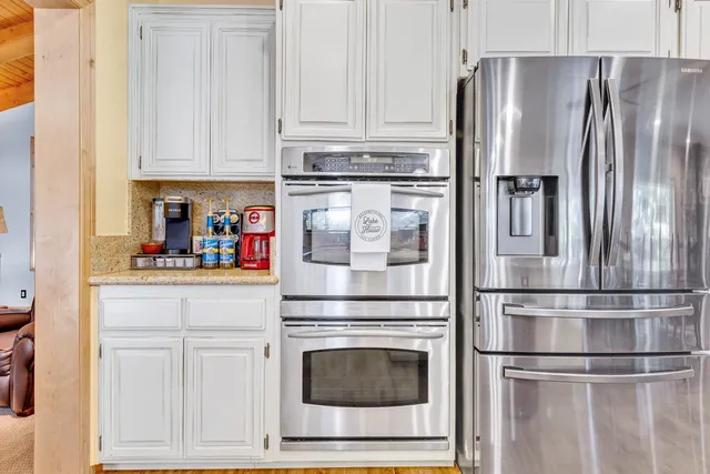 a kitchen with stainless steel appliances granite countertop a refrigerator stove and white cabinets