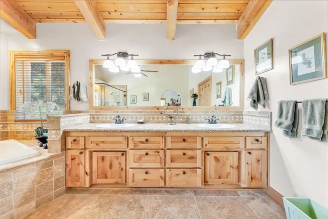 a bathroom with a granite countertop double vanity sink a mirror and bathtub