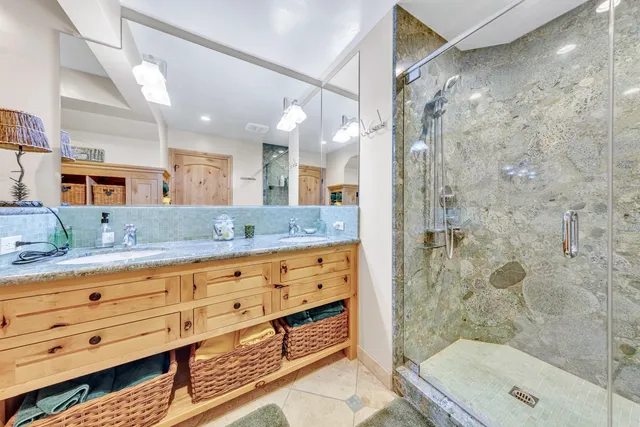 a bathroom with a granite countertop sink a mirror a bathtub and shower