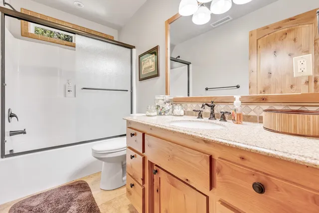 a bathroom with a granite countertop sink a toilet and a mirror