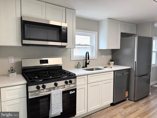 a kitchen with cabinets stainless steel appliances and wooden floor
