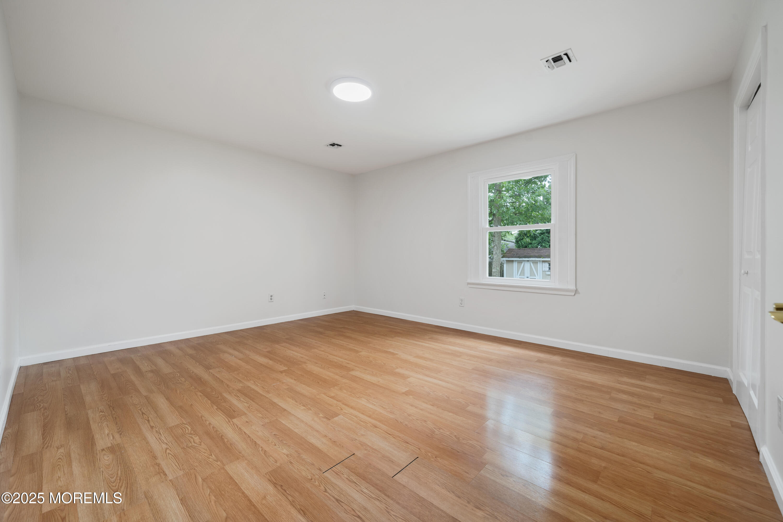 168 Stowaway Road Manahawkin, NJ 08050 - Photo 14 of 15 an empty room with wooden floor and windows