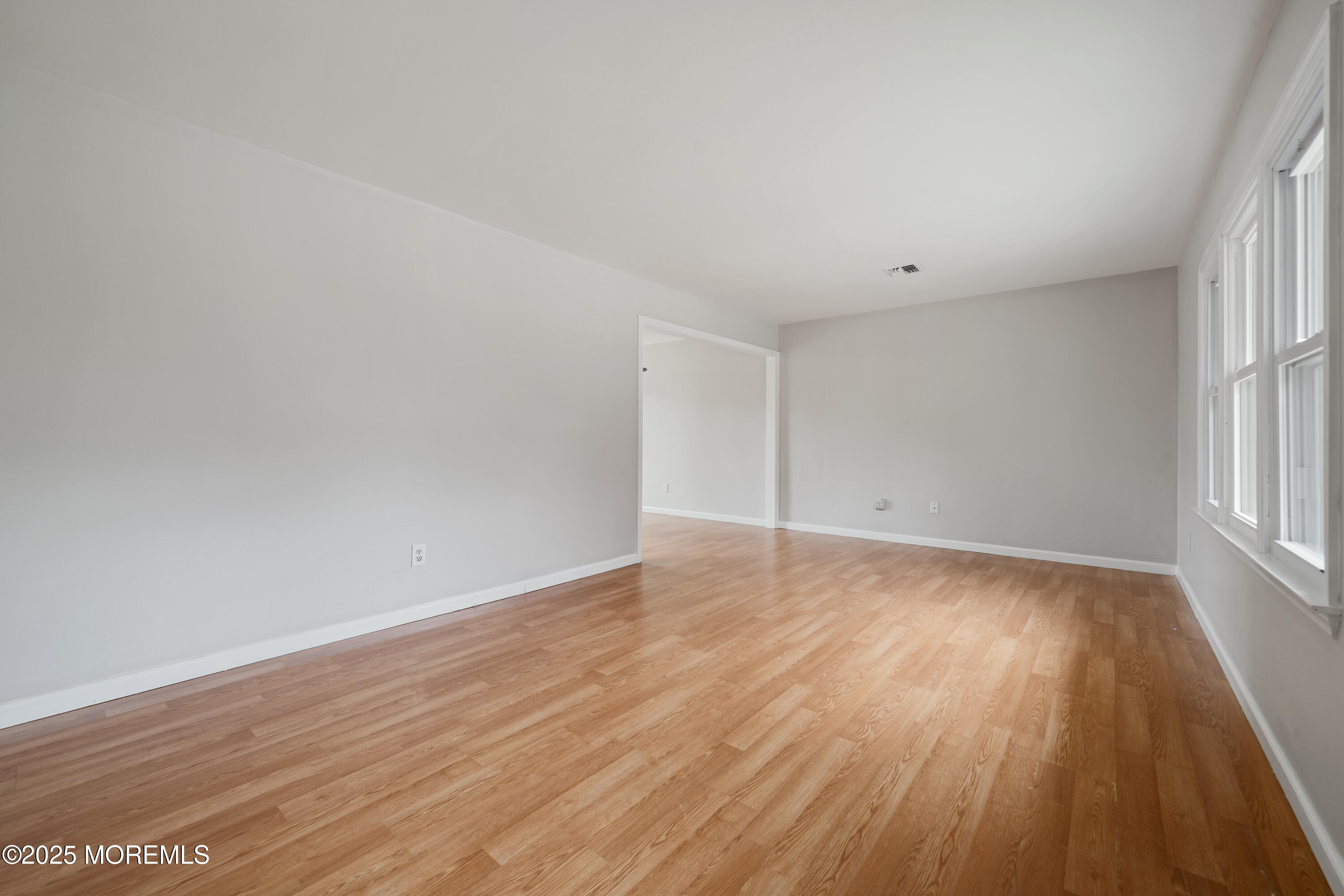 168 Stowaway Road Manahawkin, NJ 08050 - Photo 3 of 15 an empty room with wooden floor and windows