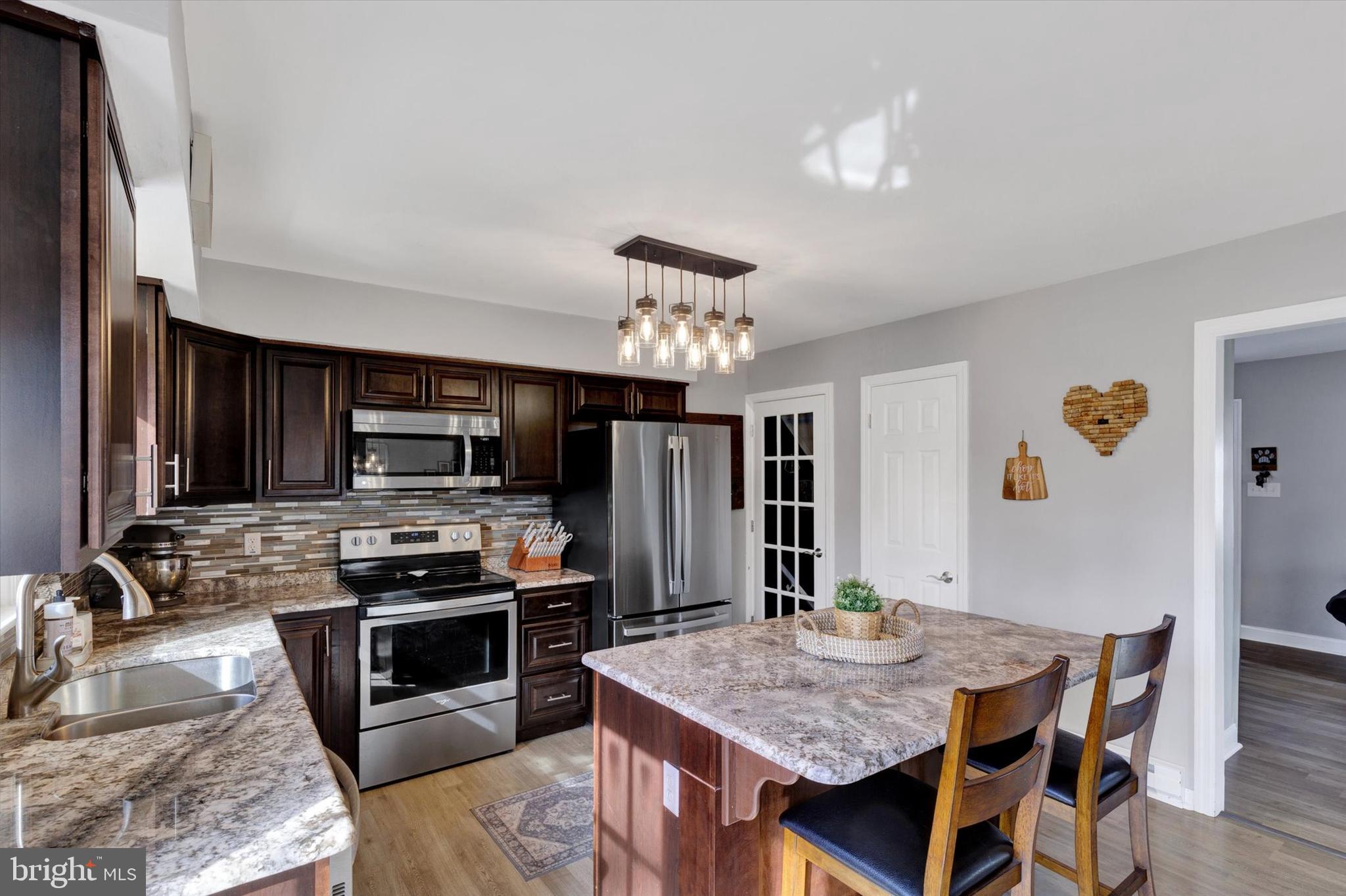 408 West 6th Street Lititz, PA 17543 - Photo 8 of 29 a kitchen with stainless steel appliances granite countertop a stove top oven a sink dishwasher a dining table and chairs with wooden floor